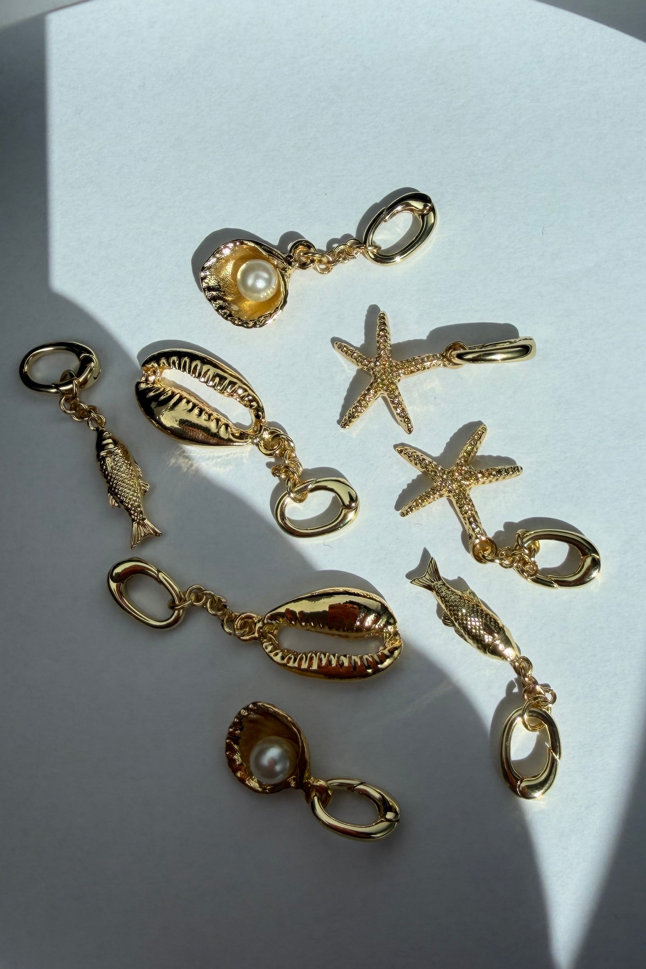 Gold jewelry charms including stars, shells, and fish 