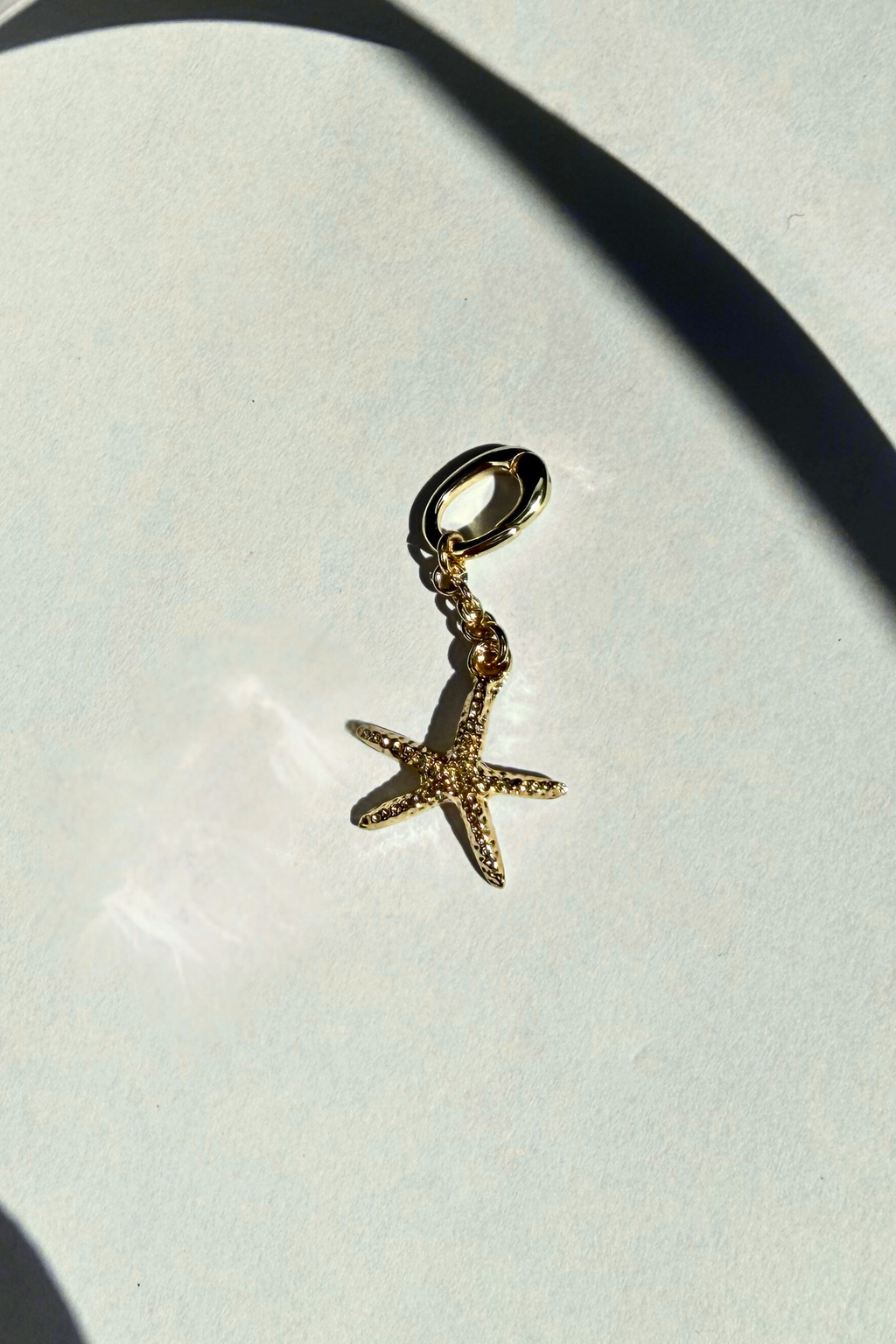 Gold starfish bikini charm on a light gray background